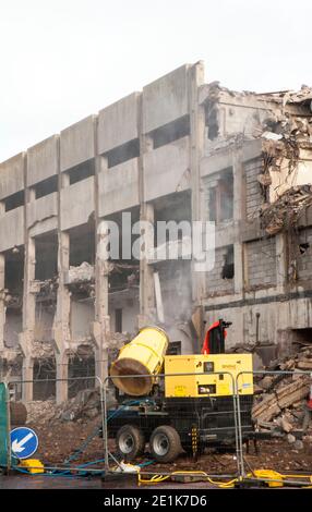 Spruzzare acqua su calcestruzzo su edificio per tenere il la polvere si abbassa mentre il parcheggio a più piani è stato demolito in seguito su una strada trafficata Foto Stock