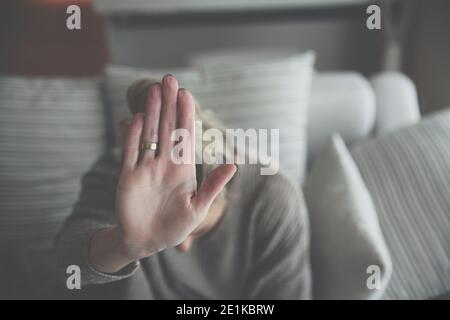 Una donna depressa, solitaria e infelice, con una mano distesa seduta da sola, si sente triste, delusa e depressa. Foto Stock