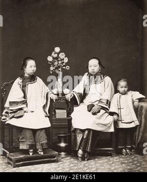 Fotografia d'annata del XIX secolo: Donne cinesi con piedi rilegati, fotografate in uno studio con un bambino piccolo. Cina. circa 1880's. Foto Stock