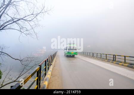 Colline himalayane - in Himachal Pradesh - ponte sul fiume Beas . Piccolo bus in movimento. Nebbia forte! Foto Stock