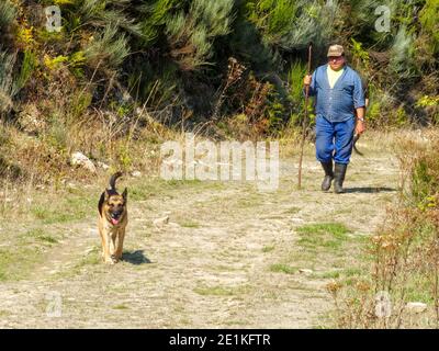 Un uomo e il suo cane stanno camminando a casa su una strada sterrata in montagna - San Fiz de Seo, Castiglia e Leon, Spagna Foto Stock