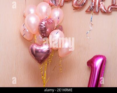 diversi palloncini di elio rosa, lettere gonfiabili sulla parete, e un gonfiabile numero uno sotto Foto Stock