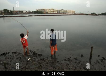 I bambini che pescano su una palude salmastra interna, in parte utilizzata come allevamento ittico nella zona costiera di Giacarta settentrionale, Giacarta, Indonesia. Foto Stock