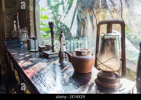 Pentole e vasi e lampada tradizionale su un tavolo di legno in un antico villaggio cinese di Gankeng Hakka Shenzhen, Cina Foto Stock