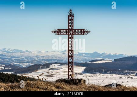 Attraversa l'altezza in cima a una collina con montagne sullo sfondo sotto un cielo azzurro. Montagne Cantal, Alvernia, Francia Foto Stock