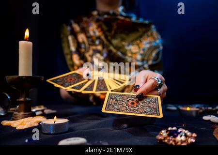 Il cassiere di fortuna tiene un ventilatore delle carte nelle sue mani e tiene fuori una carta con una mano. Primo piano. Il concetto di divinazione, magia ed esoterismo. Foto Stock