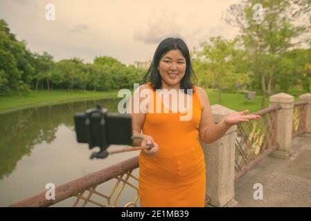 Bella donna asiatica in sovrappeso rilassante al parco nella città di Bangkok, Thailandia Foto Stock