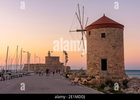 Tramonto di Rodi sulla Fortezza di San Nicola e i mulini a vento che costeggiano il porto di Mandraki, Rodi, Isola di Rodi, Grecia Foto Stock