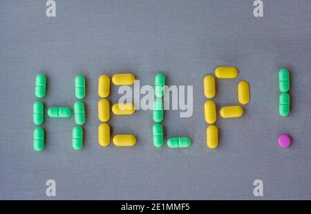 La parola AIUTO fatto di pillole multicolore su tessuto grigio sfondo Foto Stock