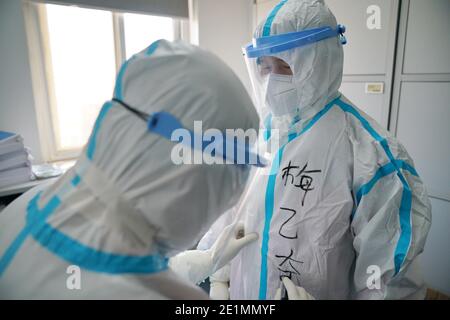 (210108) -- SHIJIAZHUANG, 8 gennaio 2021 (Xinhua) -- Zuo Lin (L), collega di Mei Yiqi, scrive il nome di Mei sulla sua tuta protettiva a Shijiazhuang, provincia di Hebei, nella Cina settentrionale, 8 gennaio 2021. Mei Yiqi, 30 anni, che lavora nel reparto logistico di Wuhan KingMed Diagnostics Group Co., Ltd., ha salutato la sua famiglia mercoledì e ha preso un treno ad alta velocità da Wuhan a Shijiazhuang per aiutare a combattere la pandemia COVID-19. Nel 2020, Mei ha partecipato successivamente al lavoro anti-pandemia a Wuhan e Chengdu, compresa la raccolta e il trasporto del samp COVID-19 Foto Stock