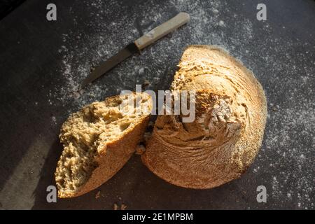 Pane artigianale appena sfornato su un tavolo. Sfondo grigio scuro con spazio per la copia. Ricetta fatta in casa per il pane di pasta acida. Foto Stock