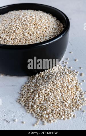 Quinoa bianca grezza in ciotola nera Foto Stock