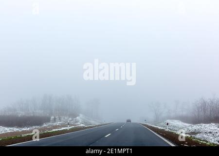 Condizioni del traffico in mattinata sulla strada invernale. La macchina è a malapena visibile. Spazio per il testo. Messa a fuoco selettiva. Foto Stock