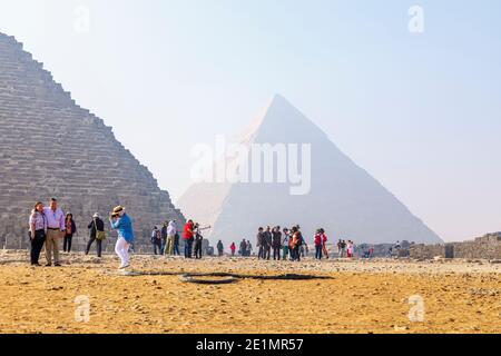 Turisti presso la Grande Piramide di fronte alla Grande Piramide di Khafre sull'altopiano di Giza, il complesso della Piramide di Giza (necropoli di Giza), il Cairo, Egitto Foto Stock