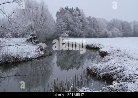 Riflessi di una scena rurale e alberi innevati nel fiume Alne, Kinwarton, vicino Alcester, Warwickshire, Regno Unito. Shakespeare's County. Foto Stock