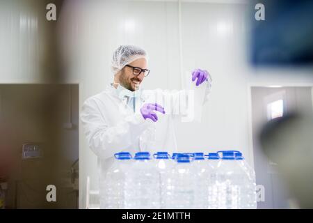 Giovane uomo in abbigliamento protettivo che lavora in laboratorio per testare la qualità dell'acqua. Foto Stock