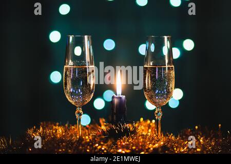 Due bicchieri di champagne e una candela con ghirlanda sfocata sfondo Foto Stock