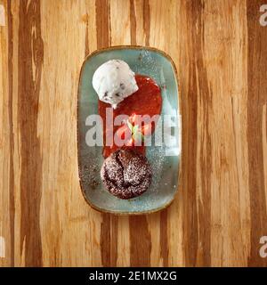 Marocchino piatto da dessert con gelato, brownie torta al cioccolato e confettura di fragole e decorate con foglie di menta, in una piastra di ceramica su un tavolo in legno e c Foto Stock