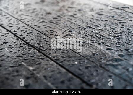 Gocce d'acqua sulla superficie nera del tavolo di legno Foto Stock