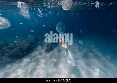 Donna freediver nuotare con meduse nell'oceano blu. Meduse nell'oceano blu Foto Stock