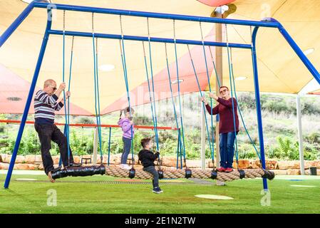 Felice famiglia sulla corda di equilibrio nel parco giochi. Foto Stock