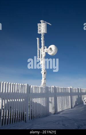 Torre meteorologica con apparecchiature di misurazione, antenna satellitare. Il dispositivo è coperto da neve surgelata, ghiaccio e rime in winte freddo e gelo Foto Stock