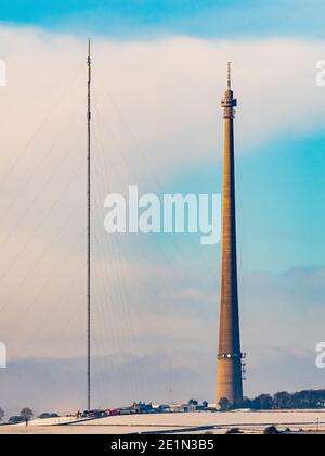 Emley Moor Mast con un albero temporaneo lungo lato nel villaggio innevato West Yorkshire di Emley. Foto Stock