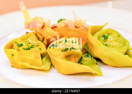 piatto di pasta all'uovo, ravioli di uova e spinaci, farciti con ripieno di ricotta e salsiccia, conditi con burro e salvia, e verdure fritte, per la festa l Foto Stock