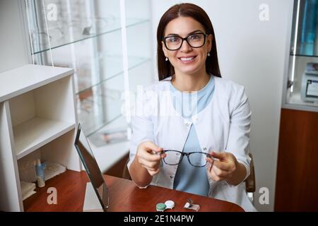 Un professionista della cura degli occhi che suggerisce un paio di occhiali Foto Stock