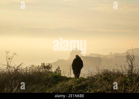 Hastings, East Sussex, Regno Unito. 8 gennaio 2021. Lone Walker al tramonto foggy a Castle Hill, Hastings, in blocco 3. Carolyn Clarke/Alamy Live News Foto Stock