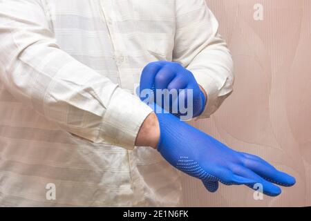 L'uomo indossa guanti in tessuto blu per lavorare. Concetto di protezione delle mani, protezione della salute. Foto Stock