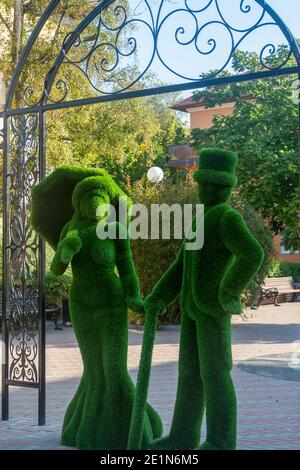 Pionersky, regione di Kaliningrad, Russia - Settembre, 2020: Figure arbustive di signora e gentiluomo da erba verde di prato. Topiario urbano. Foto Stock