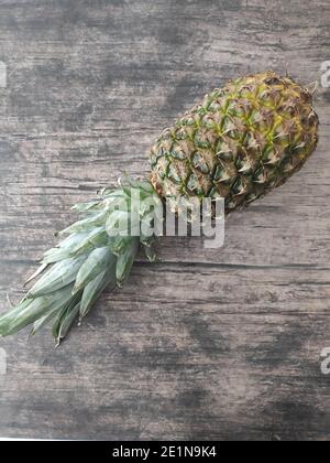 Un ananas intero adagiato su un tavolo di legno Foto Stock