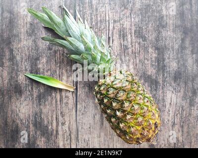 Un ananas intero adagiato su un tavolo di legno Foto Stock