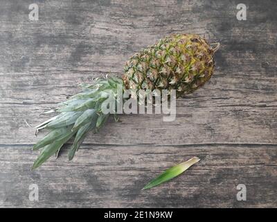 Un ananas intero adagiato su un tavolo di legno Foto Stock
