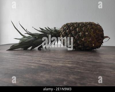 Un ananas intero adagiato su un tavolo di legno Foto Stock