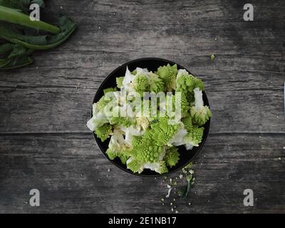 Romanesco Broccoli su una ciotola marrone su una cucina di legno tabella Foto Stock