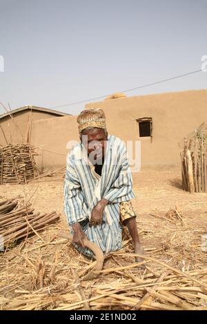 Un uomo cieco che indossa abiti tradizionali lavora sulla sua terra nel Ghana settentrionale, Africa occidentale Foto Stock