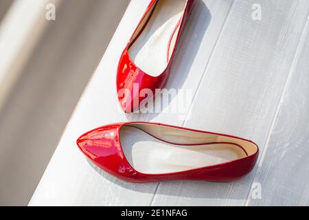 Scarpe da donna in pelle rossa su ripiano in legno bianco. Moda, minimal fashion concept, scarpe da donna, accessori. Scarpe in pelle laccata rossa da donna Foto Stock
