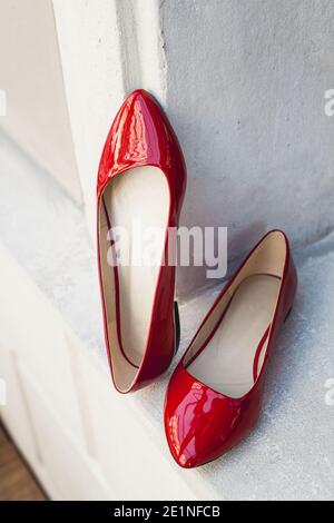 Scarpe da donna in pelle rossa su ripiano in legno bianco. Moda, minimal fashion concept, scarpe da donna, accessori. Scarpe in pelle laccata rossa da donna Foto Stock