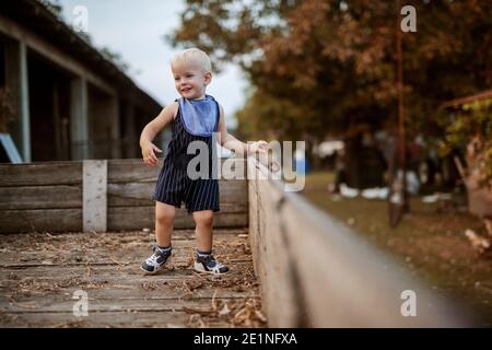 Godendo sul suo farm.Little nonni ragazzo sta divertendosi in un rimorchio di legno. Foto Stock