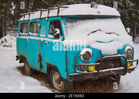 Un vecchio furgone arrugginito dell'ambulanza si trova in una radura innevata in una giornata invernale nuvolosa. Foto Stock