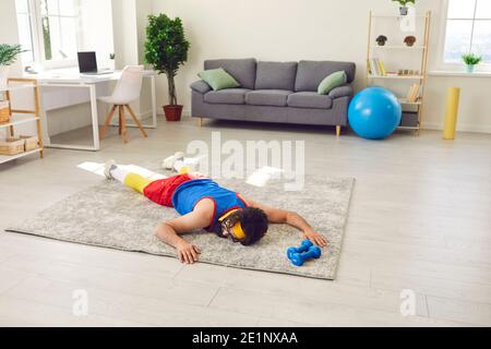 Giovane sfinito sdraiato sul pavimento dopo aver fallito e dato allenamento fitness Foto Stock