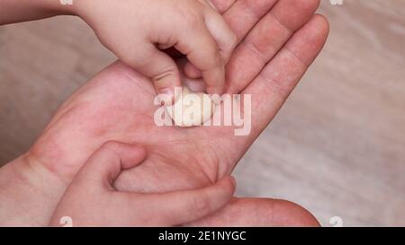 Il figlio piccolo mette un piccolo cuore di gesso nella mano del suo papà, concetto di relazione di famiglia. Foto Stock