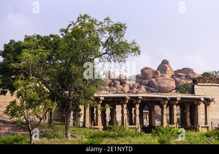 Hampi, Karnataka, India - 5 novembre 2013: Tempio di Badavilinga nel suo ambiente naturale di vegetazione verde e enormi massi marroni. Piccolo rovinoso b Foto Stock