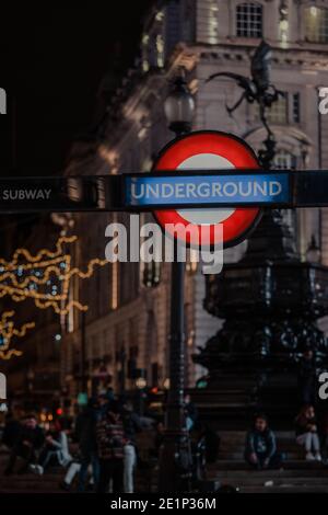 Londra, Regno Unito - 19 novembre 2020: Segnale della metropolitana di Londra all'ingresso della stazione Piccadilly Circus, Londra, di notte. La metropolitana di Londra è l'olde Foto Stock