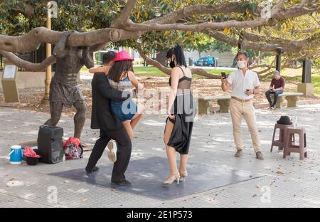 I turisti con maschere facciali posano con ballerini di tango di strada con maschere facciali durante la pandemia del Covid-19 a Recoleta, Buenos Aires, Argentina Foto Stock