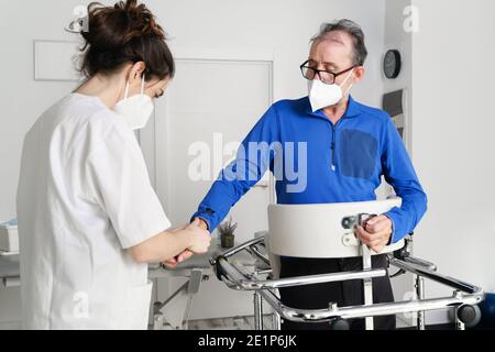 infermiera femminile, tenendo la mano del paziente, paziente di supporto disabili sedersi su sedia a rotelle in ospedale, giovane medico che assiste paziente paralizzato. Foto di alta qualità Foto Stock