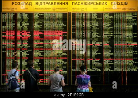 KIEV - UCRAINA - 10 AGOSTO 2014: I passeggeri che guardano le partenze elettroniche e gli arrivi salmano nella stazione ferroviaria principale di Kiev, preparandosi Foto Stock