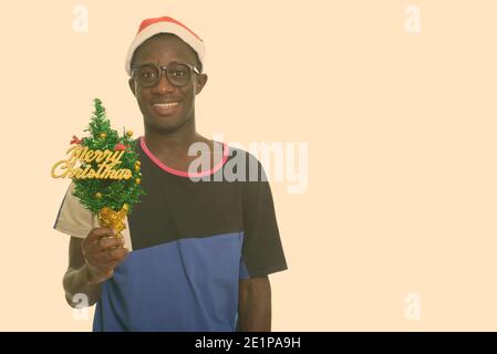 I giovani africani felice uomo sorridente tenendo Merry Christmas tree pronto per Natale Foto Stock